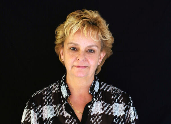 Gabrielle Buergi vom Verkaufsinnendienst, verantwortlich für die Kundenbestellabwicklung, posiert vor einem schwarzen Hintergrund.