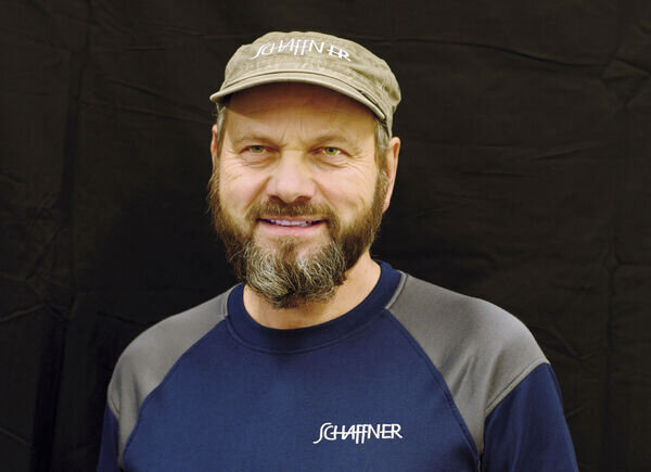 Paul Scheidegger, Mitarbeiter im Logistikbereich, posiert vor einem schwarzen Hintergrund in einem Schaffner GF AG-T-Shirt und Kappe.